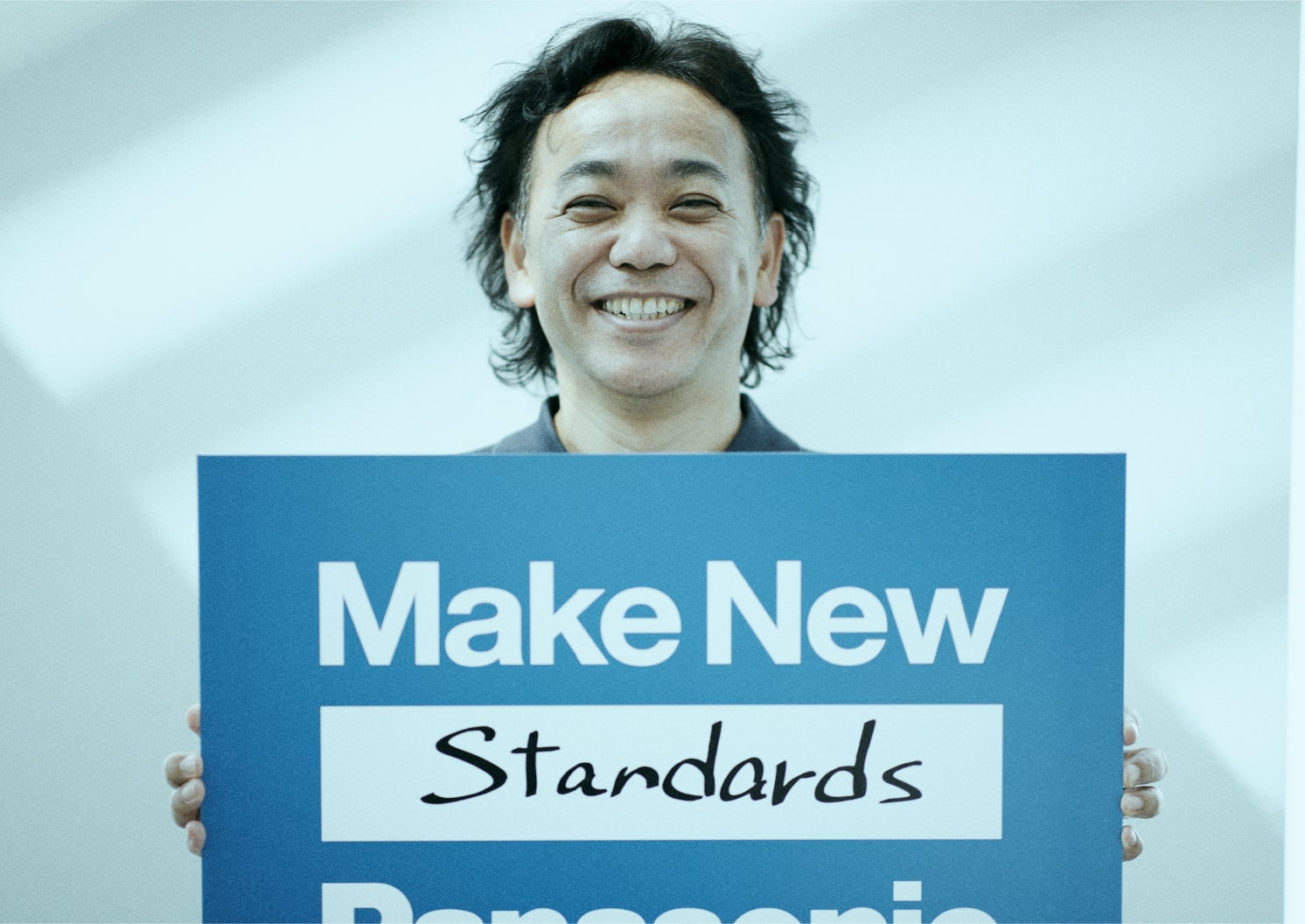 Make New Standardsのパネルを持つ パナソニック ホールディングス株式会社執行役員デザイン担当、パナソニック株式会社執行役員カスタマーエクスペリエンス担当(兼)デザイン本部長 臼井重雄 氏 | Make New Magazine「未来の定番」をつくるために、パナソニックのリアルな姿を伝えるメディア